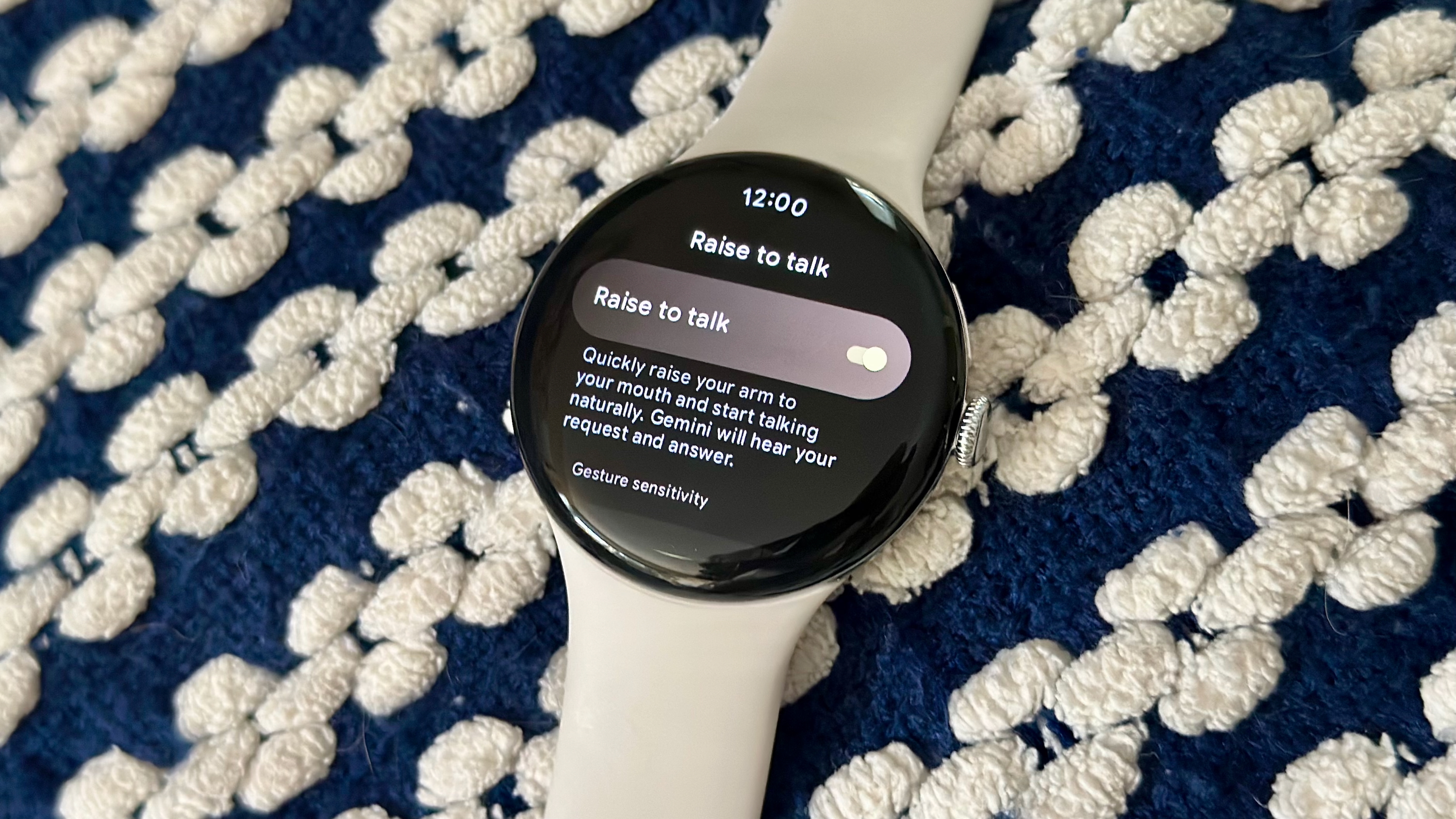 Μια φωτογραφία του Google Pixel Watch 4 σε μια κουβέρτα που δείχνει το "Σηκωθείτε για να μιλήσετε" μενού ρυθμίσεων, με ενεργοποιημένη τη λειτουργία.