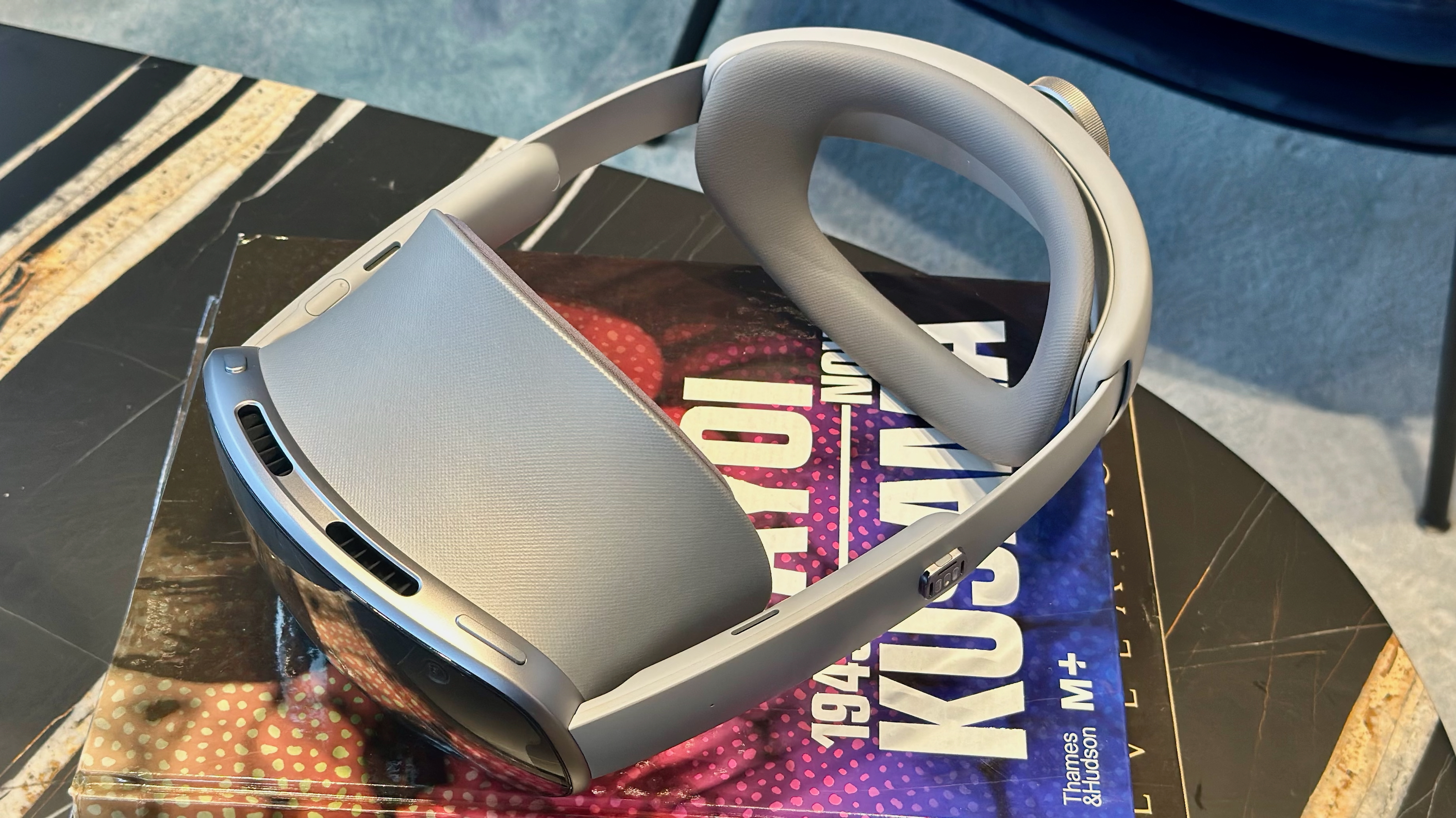 A top-down photo of the Samsung Galaxy XR headset sitting on a pile of books.