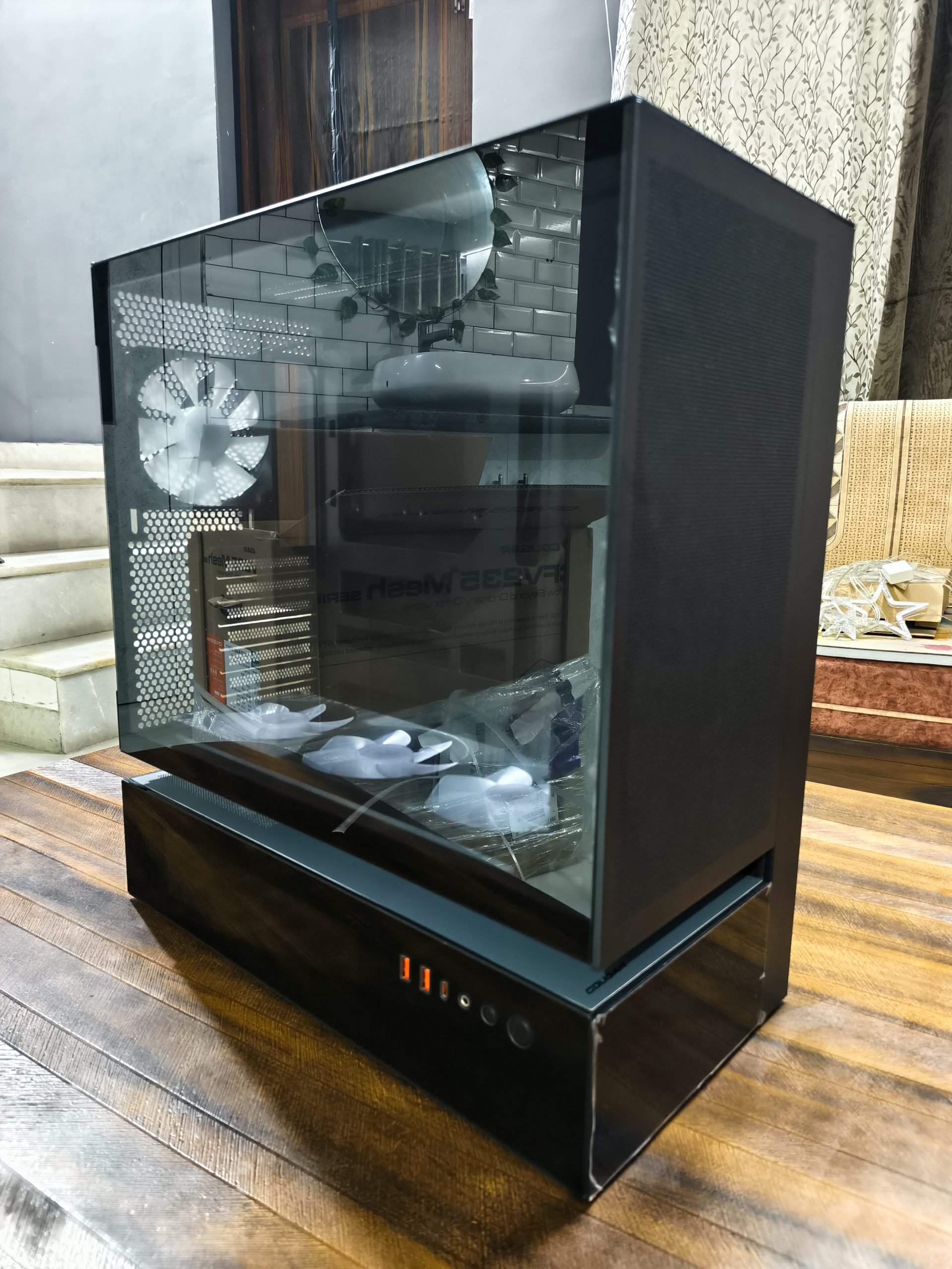 Μια σκούρα γυάλινη θήκη υπολογιστή με ορατούς ανεμιστήρες και θύρες μπροστινού πίνακα σε ξύλινο τραπέζι.