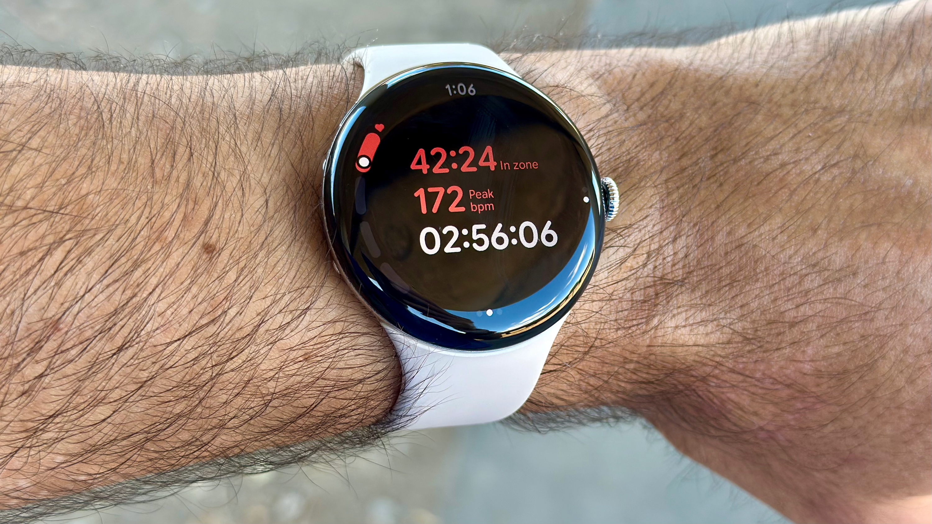 Κοντινό πλάνο του Google Pixel Watch 4 που δείχνει την προβολή εκτέλεσης ζώνης HR, με α "ώρα στη ζώνη" stat με κόκκινο, με α "κορυφή" HR 172 κάτω από αυτό, μετά ο τρέχων χρόνος εκτέλεσης σε λευκό.