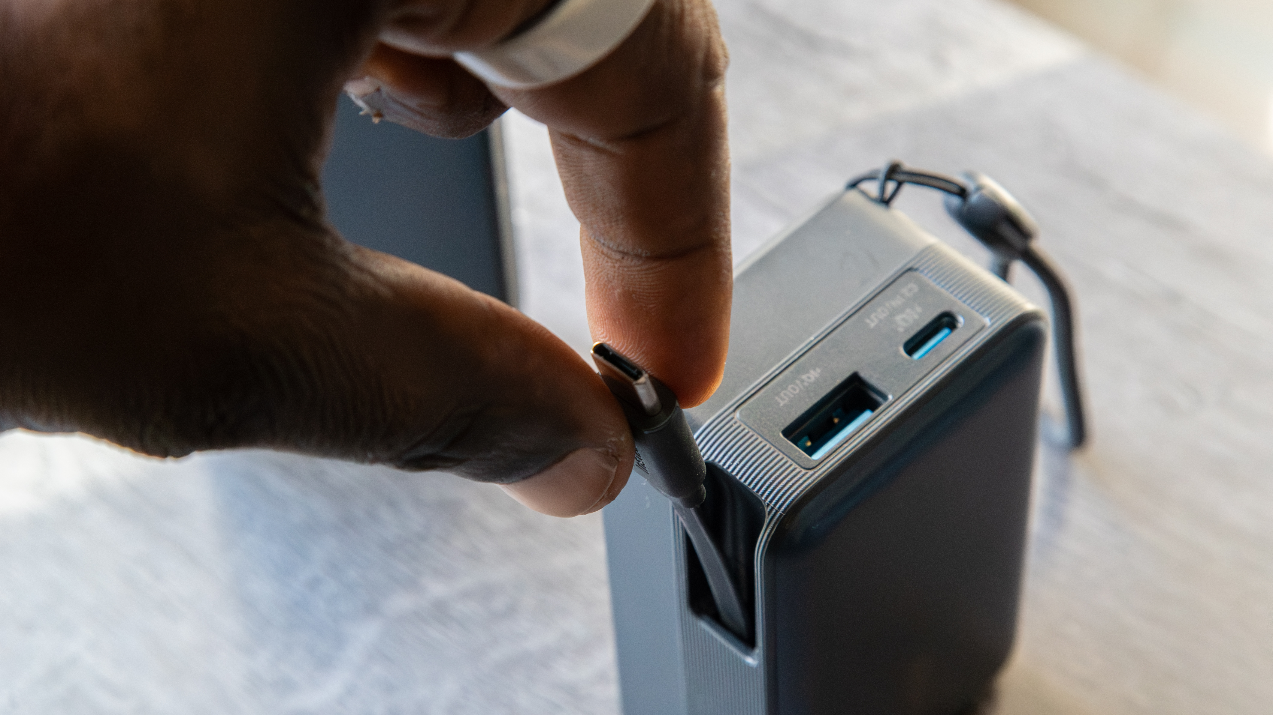 Ένα χέρι που τραβάει το ανασυρόμενο καλώδιο USB-C Anker Nano Power Bank (A1638).