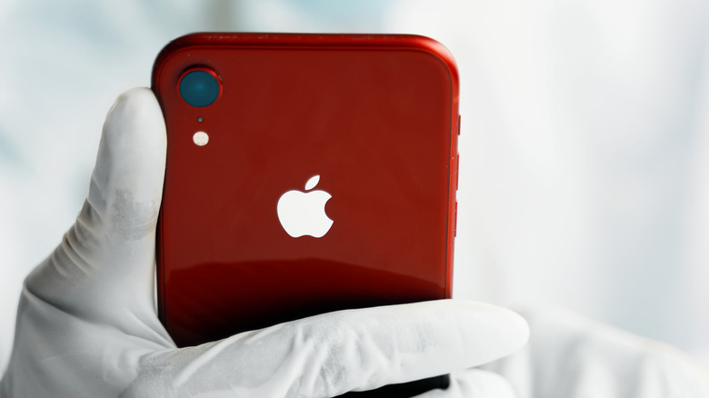 Ένα άτομο που κρατά ένα iPhone XR ενώ φοράει γάντια