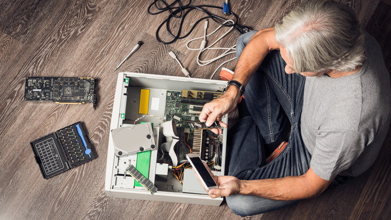 Μια φωτογραφία από πάνω προς τα κάτω ενός άνδρα που συναρμολογεί έναν επιτραπέζιο υπολογιστή.