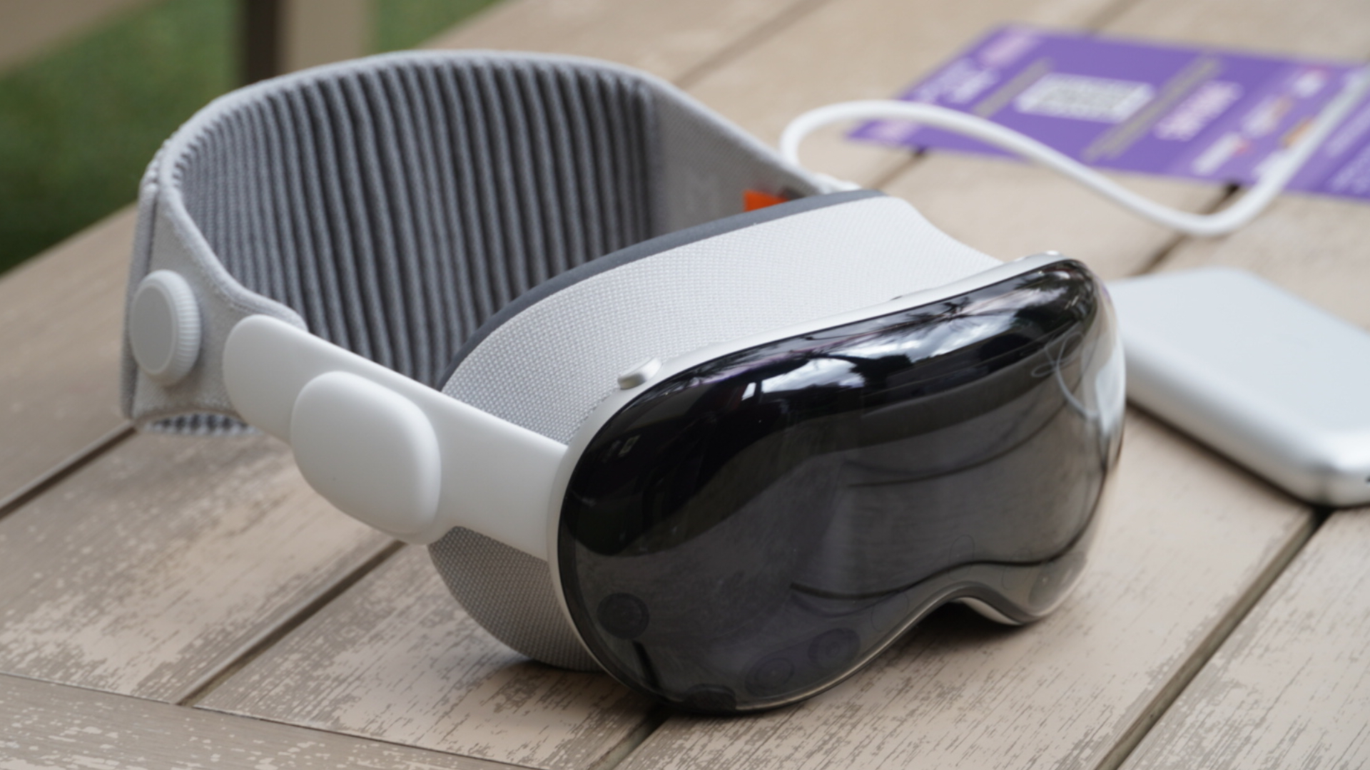 Apple Vision Pro σε εξωτερικούς χώρους σε τραπέζι με αξεσουάρ.