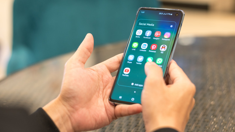 άτομο που χρησιμοποιεί smartphone με εικονίδια εφαρμογών κοινωνικών μέσων που εμφανίζονται στην οθόνη