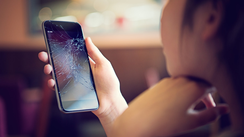 Γυναίκα που κοιτάζει το smartphone με τη σπασμένη οθόνη.