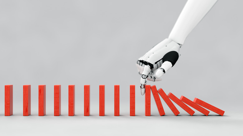 Ανθρωποειδές χέρι ρομπότ που χτυπά πάνω από ντόμινο.