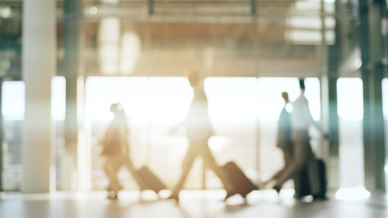 Άνθρωποι που τραβούν και σπρώχνουν αποσκευές μέσα από ένα αεροδρόμιο.