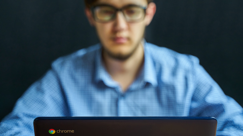 Ένας νεαρός άνδρας ξεθώριασε στο παρασκήνιο χρησιμοποιώντας ένα Chromebook.