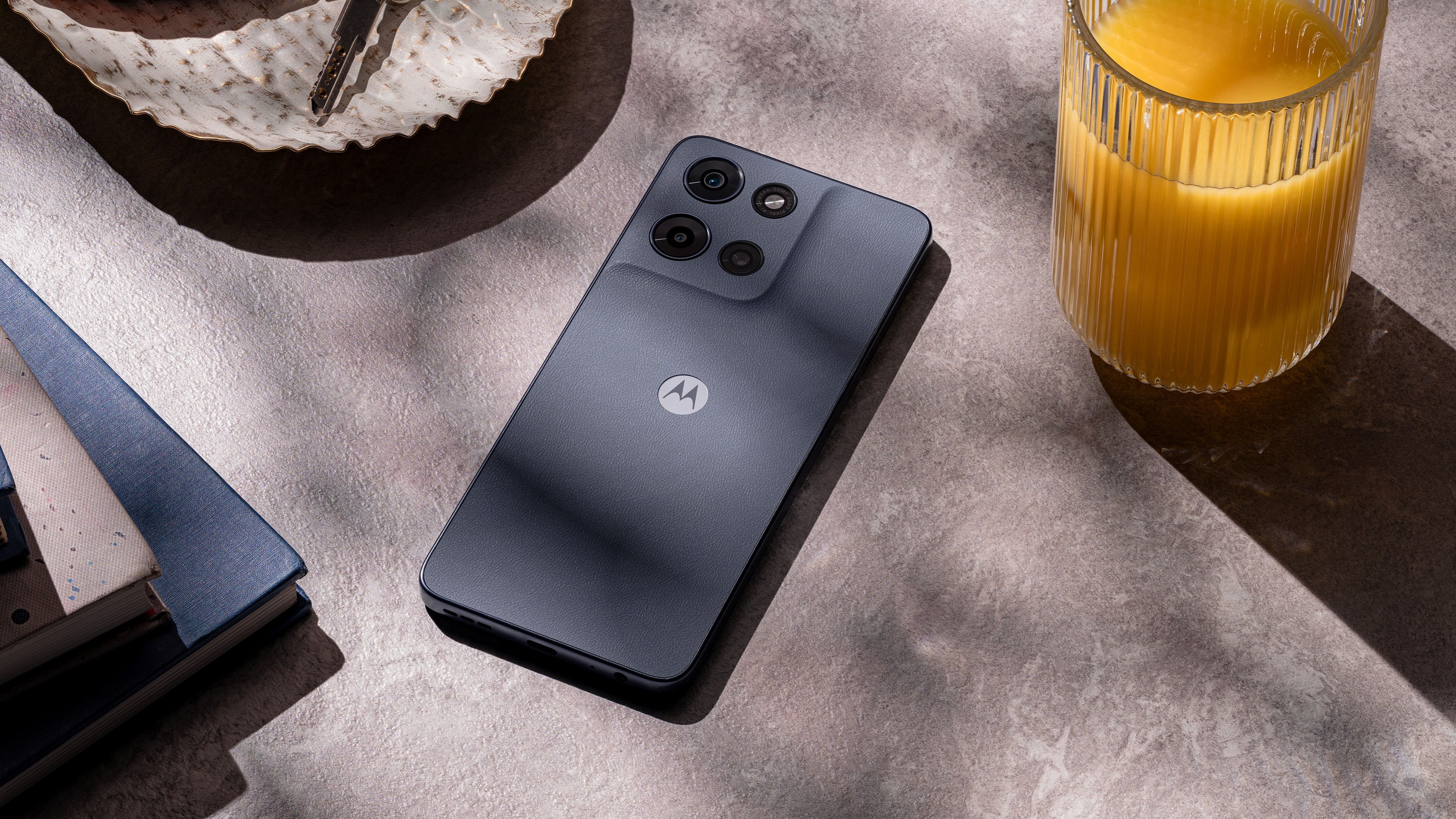 Moto G 2026 σε μια επιφάνεια δίπλα σε ένα ποτήρι χυμό πορτοκαλιού