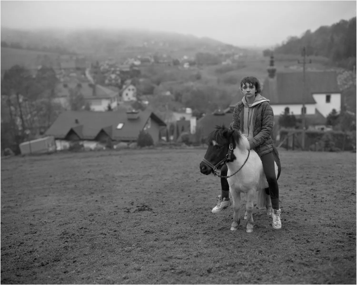 αγόρι σε ένα μικροσκοπικό άλογο μπροστά από την αγροτική πόλη