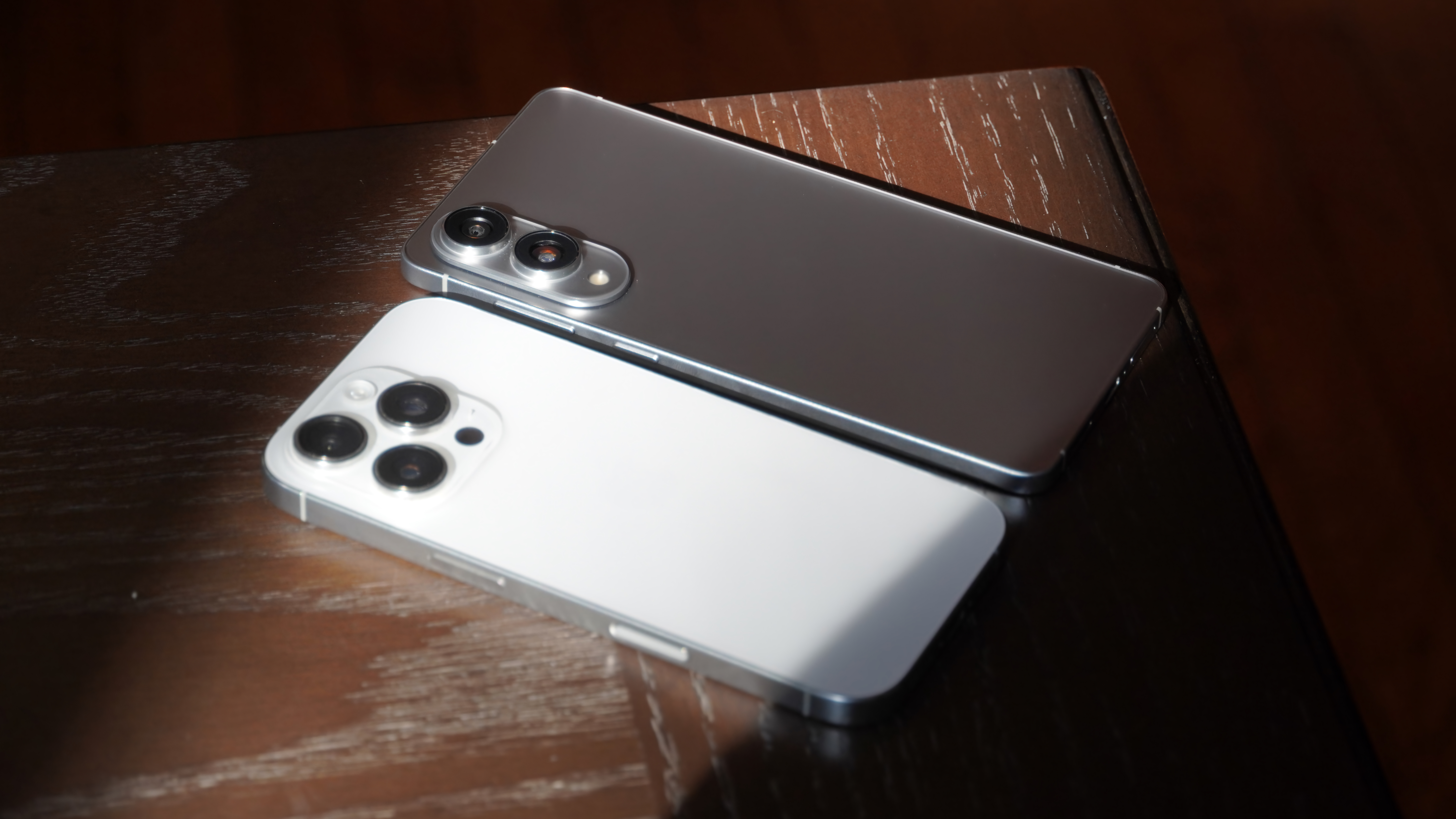 Ένα iPhone 16 Pro με τηλεφακό δίπλα σε Samsung Galaxy S25 Edge χωρίς έναν.