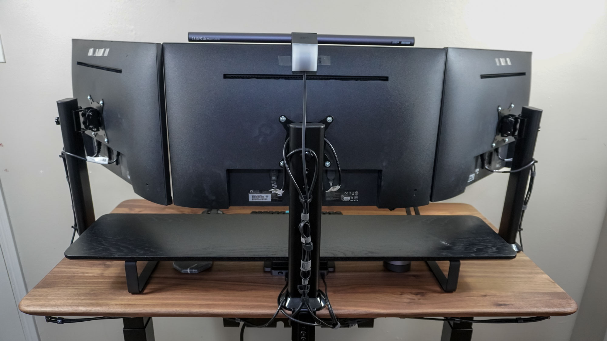 Μια ρύθμιση τριπλής οθόνης που φαίνεται από πίσω δείχνει τη διαχείριση καλωδίων της