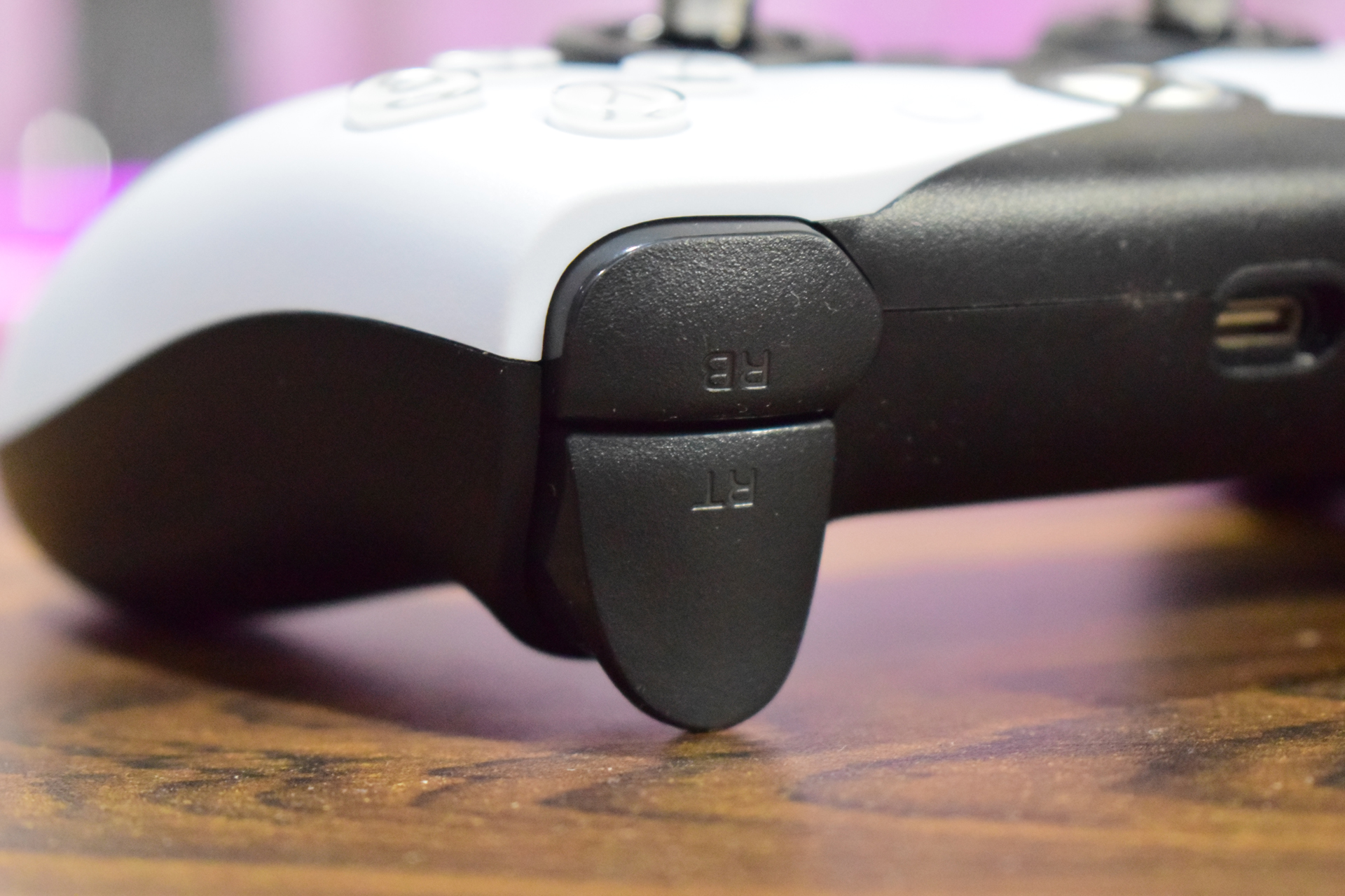 Ικανοποιητικός ελεγκτής προϋπολογισμού για PC και Xbox Ένα κοντινό πλάνο ενός λευκού και μαύρου ελεγκτή παιχνιδιών που δείχνει τον δεξιό προφυλακτήρα με την ένδειξη «RB» και τη δεξιά σκανδάλη με την ένδειξη «RT», με μια θύρα USB-C ορατή στο πλάι.