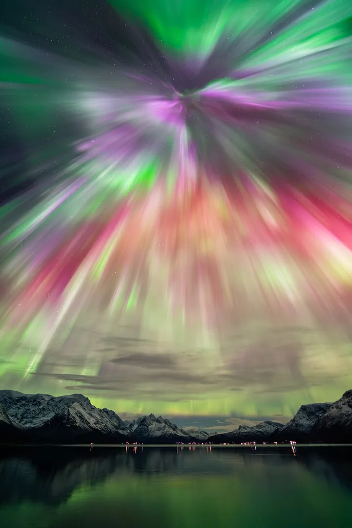 a yellow, red, purple, andgreen aurora shines over muntains