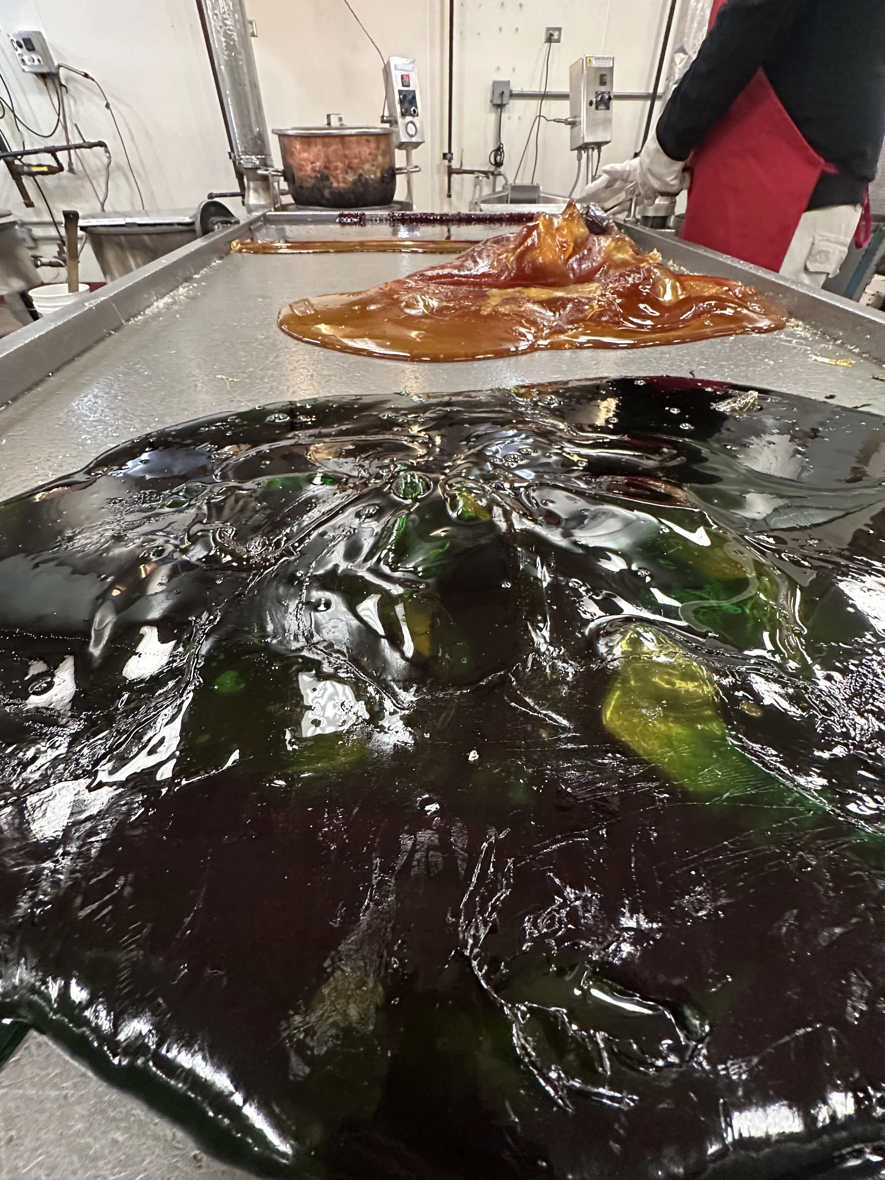 μια πορτοκαλί και πράσινη σταγόνα υγροποιημένης καραμέλας σε ένα τραπέζι από χάλυβα