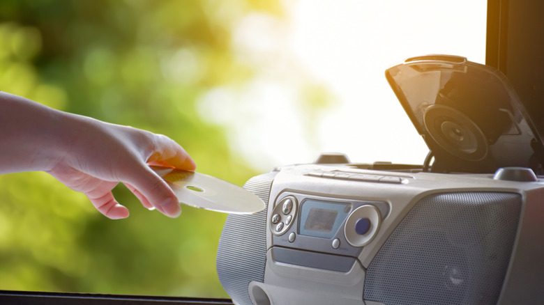 Ένα χέρι που βάζει ένα CD σε ένα boombox.