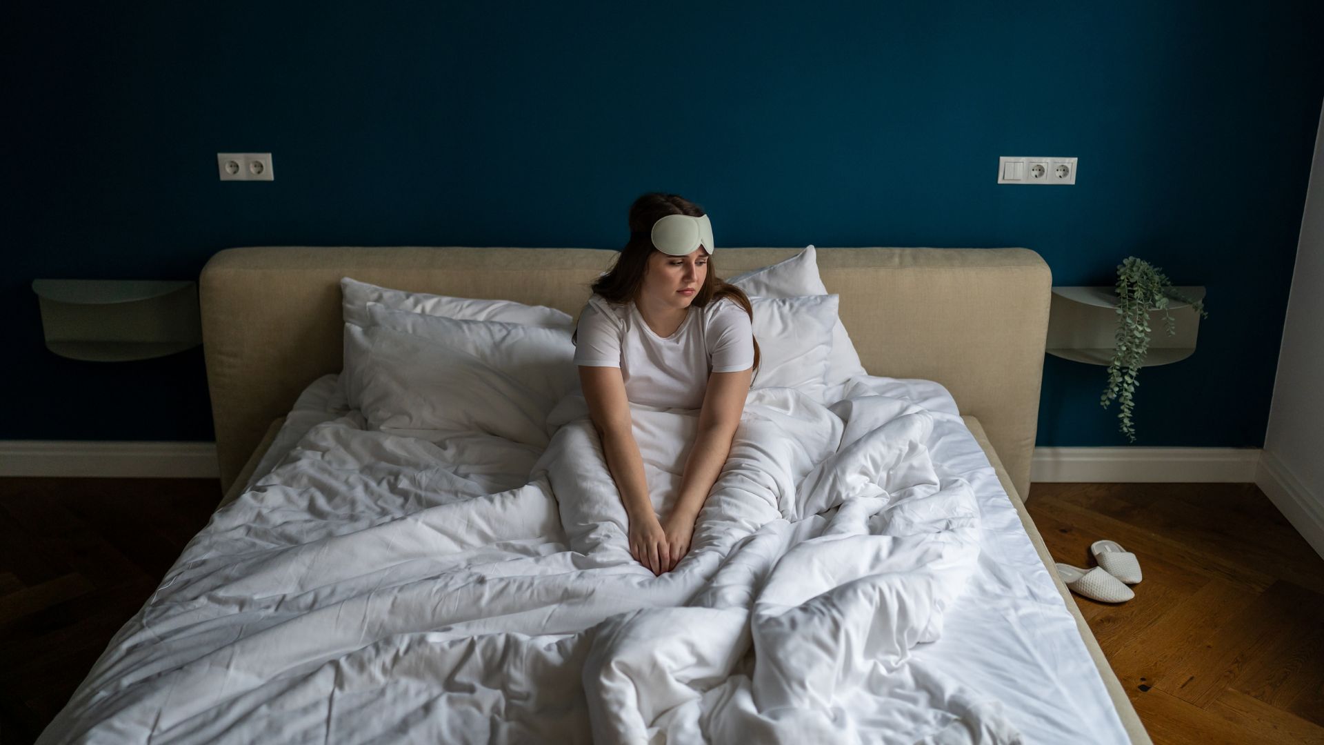 Μια γυναίκα κάθεται στο κρεβάτι στη μέση της νύχτας και φαίνεται δυστυχισμένη.