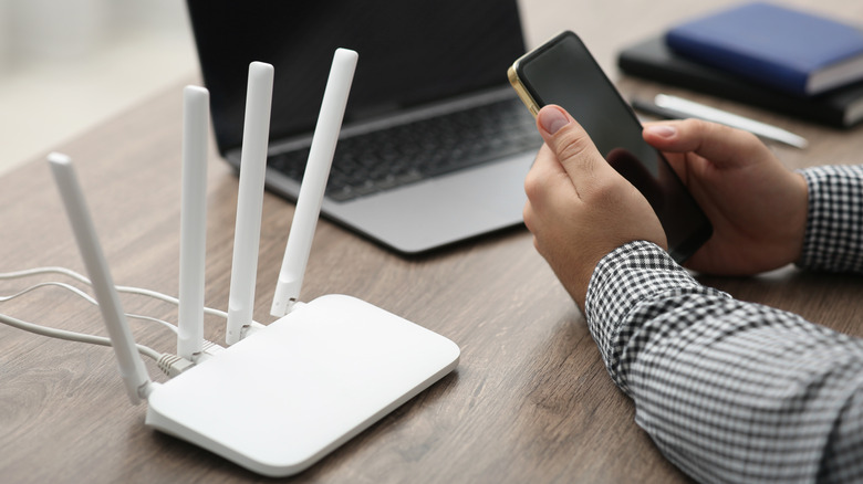 Άτομο που χρησιμοποιεί δρομολογητή Wi-Fi για να συνδέσει ένα smartphone στο διαδίκτυο