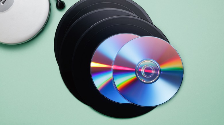 Δίσκοι βινυλίου και CD στοιβαγμένα σε ένα τραπέζι δίπλα σε ένα CD player