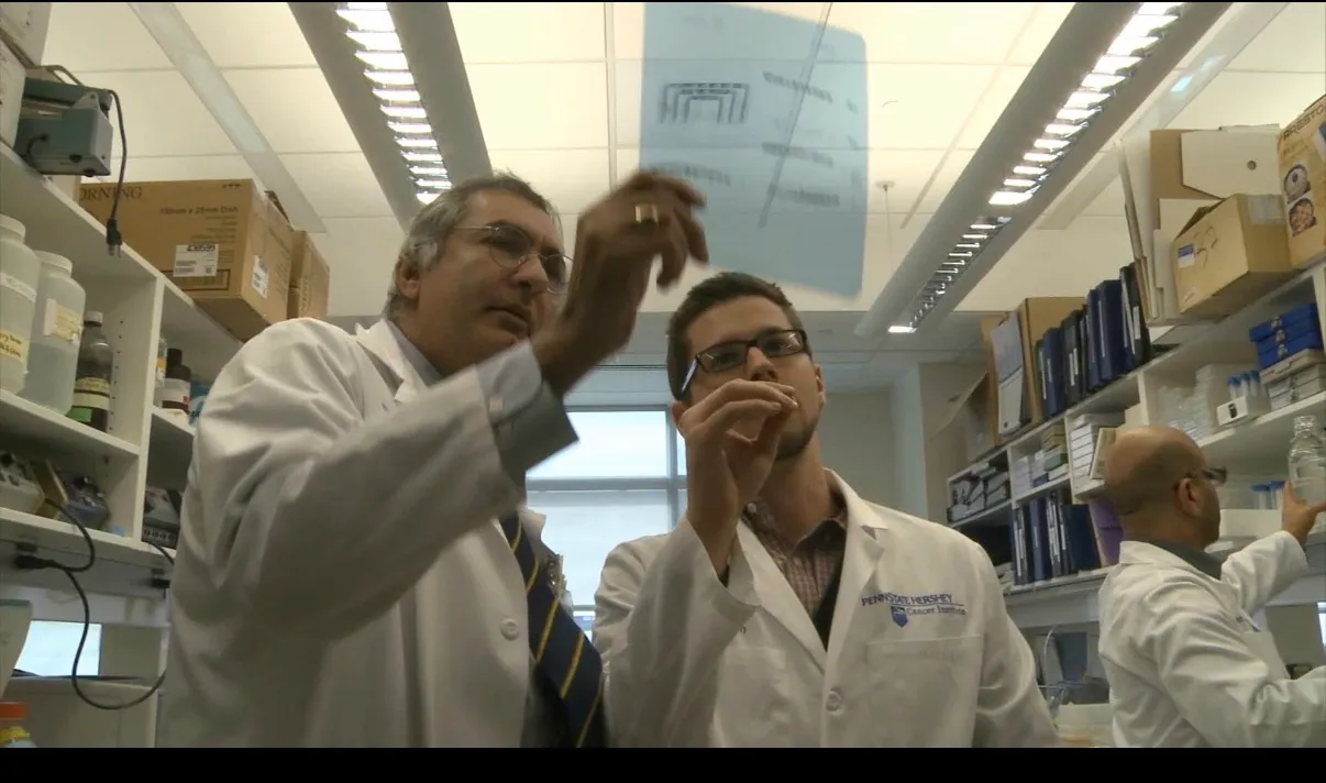 δύο άντρες με παλτό εργαστηρίου που εργάζονται σε ένα εργαστήριο