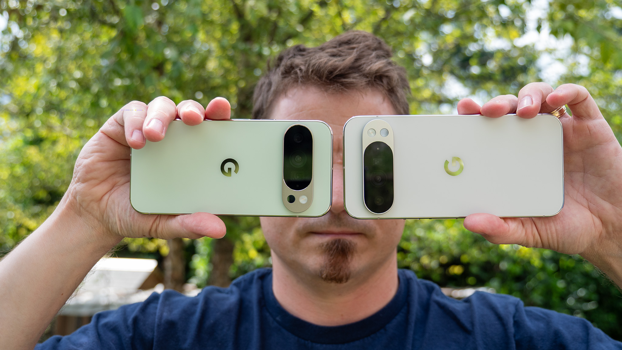 Κρατώντας ψηλά τα Jade Google Pixel 10 Pro και Porcelain Pixel 10 Pro XL για να δείξετε τις πλάτες και τα νησιά της κάμερας