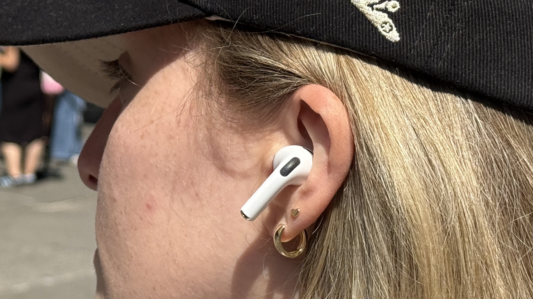 Γυναίκα με καπέλο που φορά τα Apple AirPods Pro 3 έξω στον ήλιο