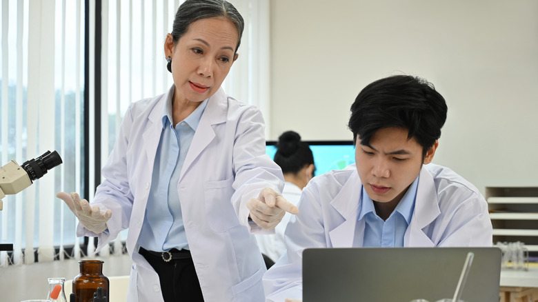 επιστήμονες συζητούν τα ευρήματά τους, κοιτάζοντας ένα φορητό υπολογιστή