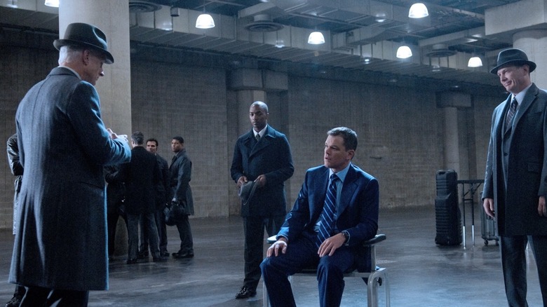 Ο Thompson (Terence Stamp) μιλά με τον David Norris (Matt Damon) ενώ ο (Harry Mitchell) στέκεται πίσω του περιτριγυρισμένος από άνδρες του Adjustment Bureau στο The Adjustment Bureau