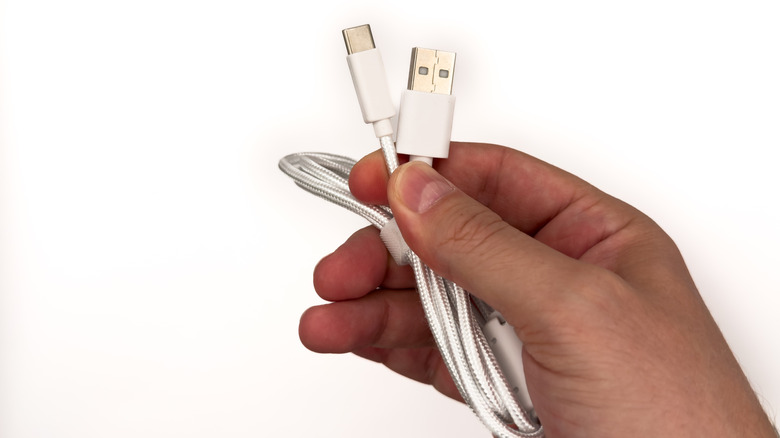 Ένα χέρι κρατά καλώδια USB Type-A και USB Type-C.