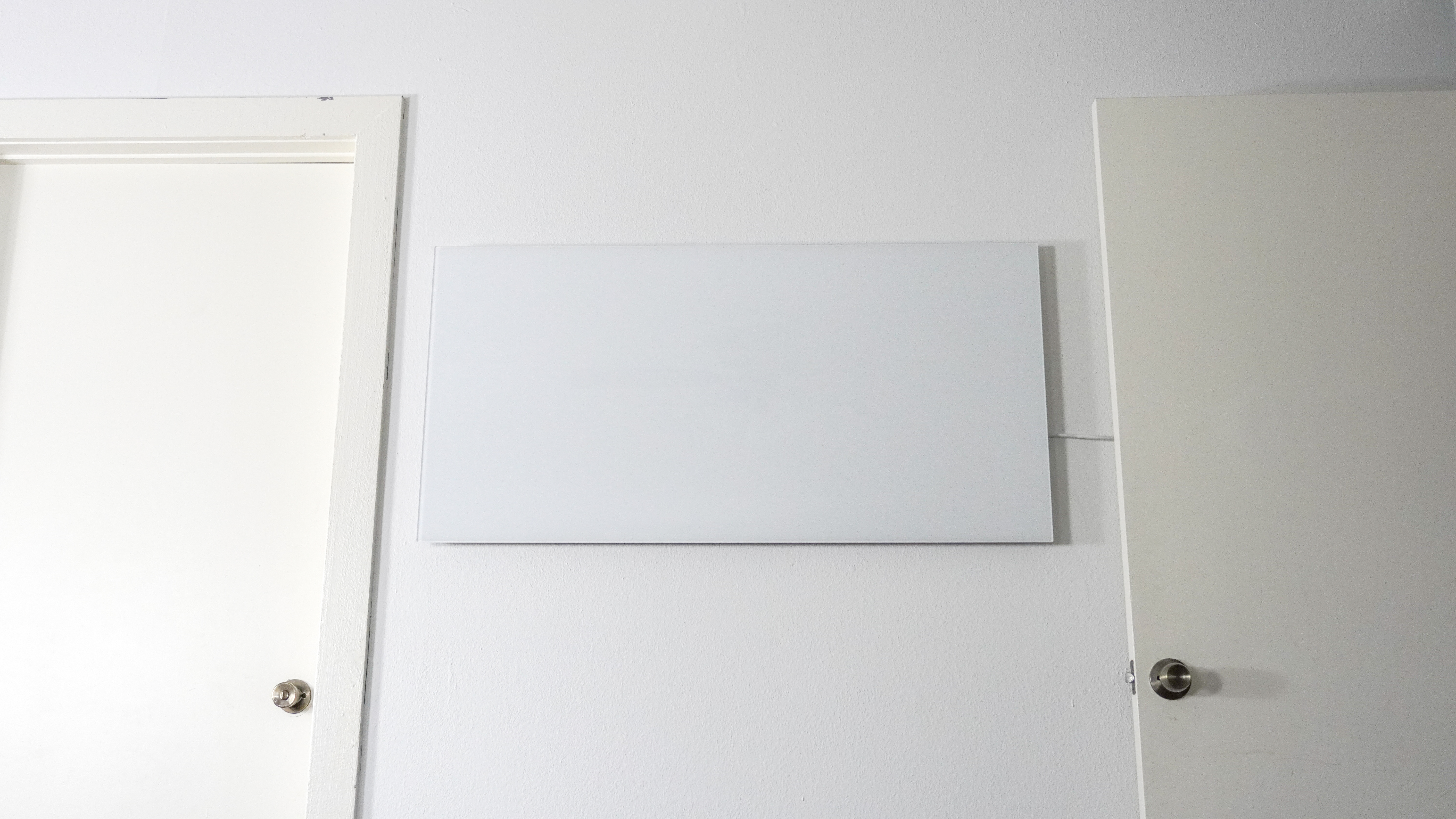 Μια ευρεία λήψη της υπέρυθρης θερμάστρας Boldr Kelvin τοποθετημένη σε έναν τοίχο ανάμεσα σε δύο πόρτες