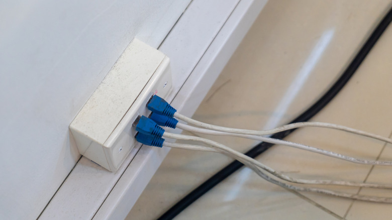 Άτομο που συνδέει ενσύρματο καλώδιο Ethernet στο πίσω μέρος του δρομολογητή.