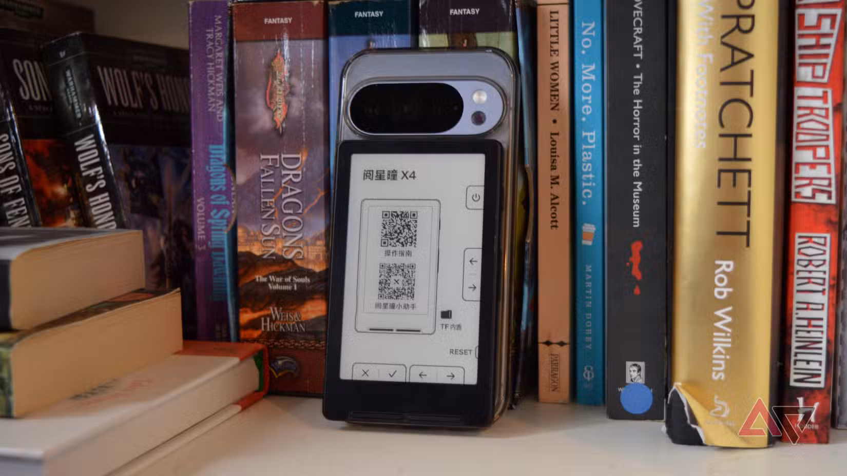 Το Xteink X4 στο πίσω μέρος ενός Pixel 10 Pro, στηριγμένο σε ένα ράφι.