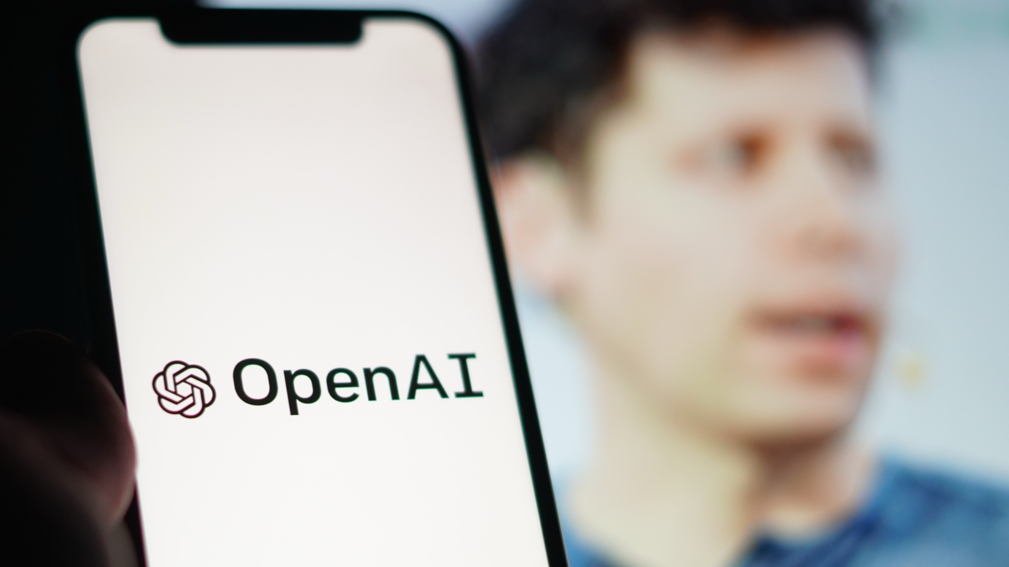 Ένα τηλέφωνο που λέει OpenAI με τον Sam Altman πίσω του