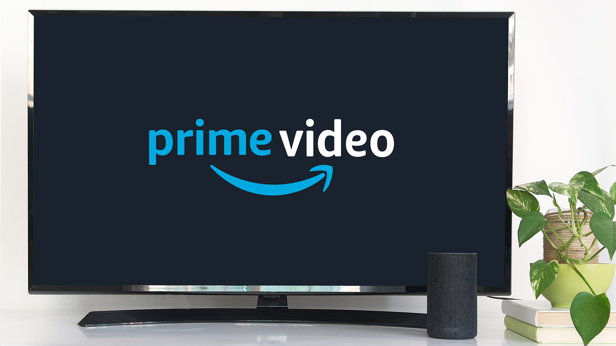 Το λογότυπο Prime Video βρίσκεται σε μια τηλεόραση δίπλα σε ένα έξυπνο ηχείο της Amazon και σε ένα φυτό