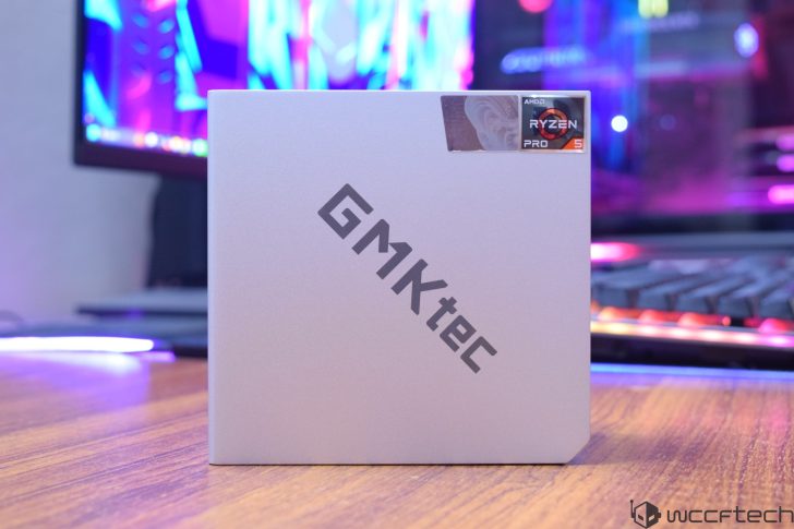 A GMKtec compact PC with an AMD Ryzen 5 Pro processor sticker is displayed on a desk with colorful LED lights in the background.