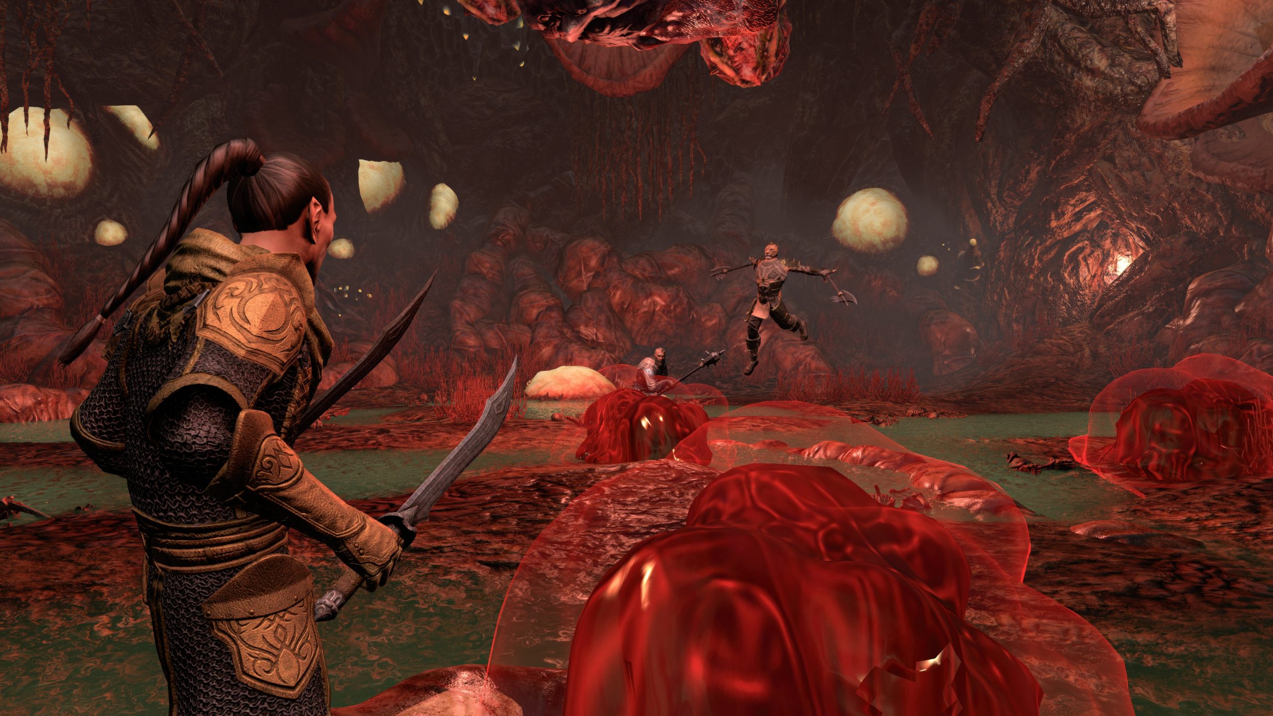 A character in The Elder Scrolls V: Skyrim stands ready with a sword in a reddish cavern while another character leaps through the air wielding dual axes.