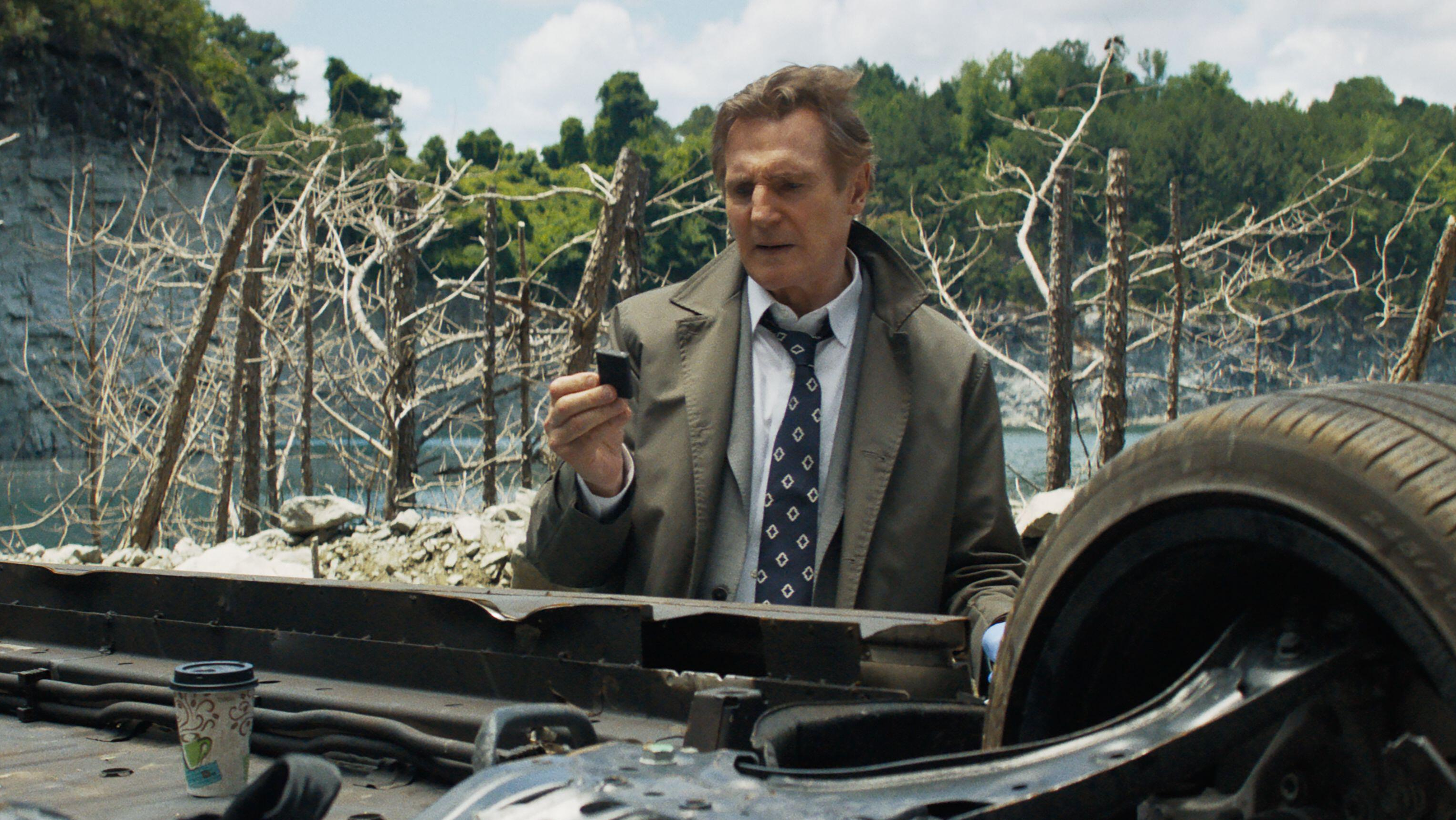 Ο Frank Drebin Jr (Liam Neeson) επιθεωρεί ένα συντρίμμι αυτοκινήτου σε μια σκηνή από "Το γυμνό όπλο" (2025)