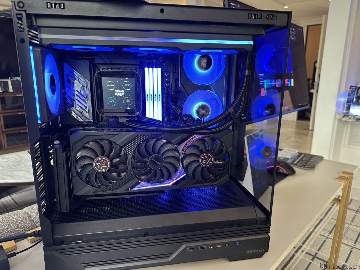 An ASRock gaming PC with RGB lighting features a prominent graphics card with dual fans and a visible cooler display labeled 'ASRock'.