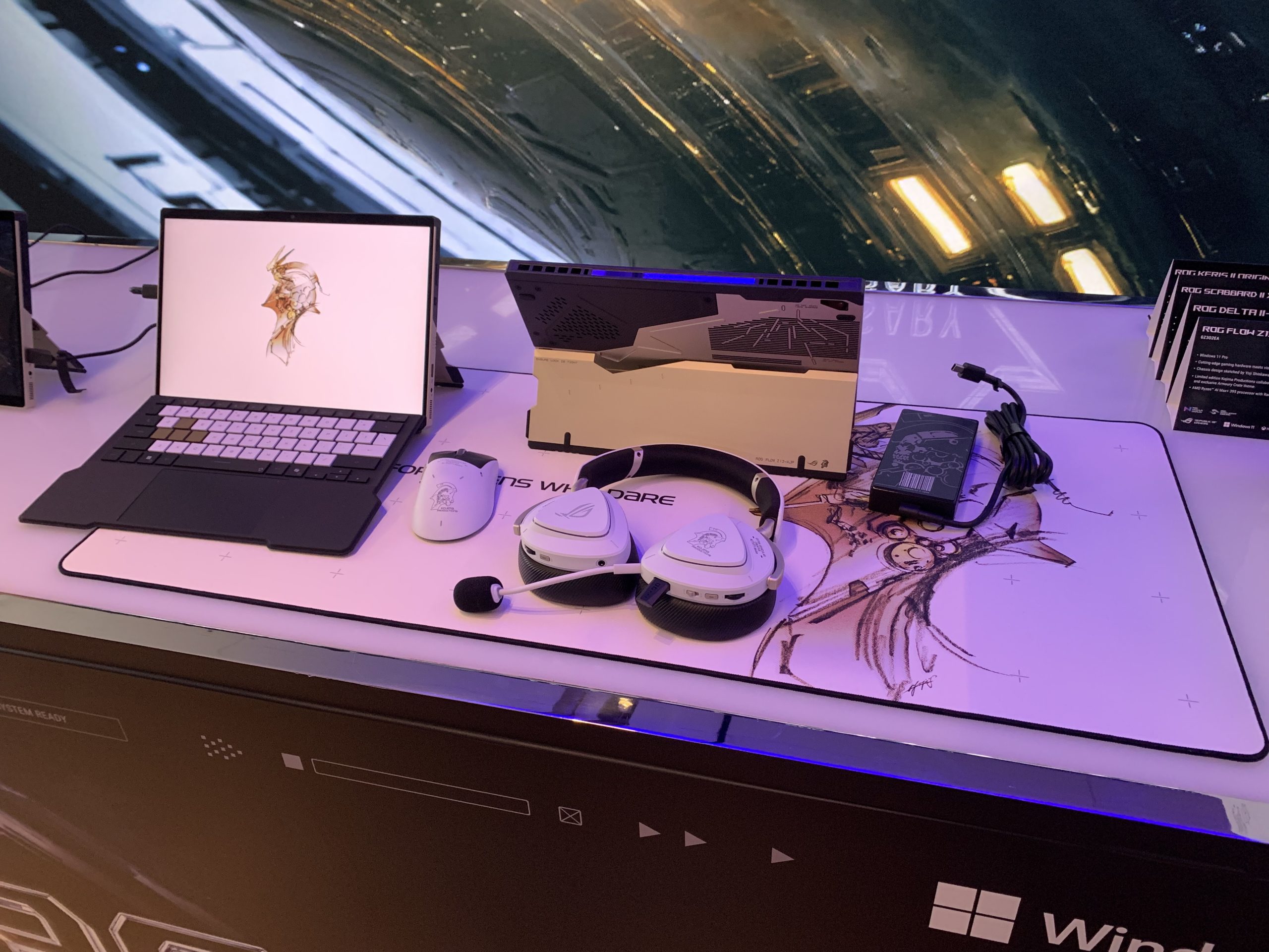 Ένας φορητός υπολογιστής ASUS ROG Flow Z13 εμφανίζεται σε ένα γραφείο με λευκά αξεσουάρ παιχνιδιών ROG, όπως ένα ποντίκι και ένα ακουστικό, και ένα μεγάλο mouse pad με έργα τέχνης.