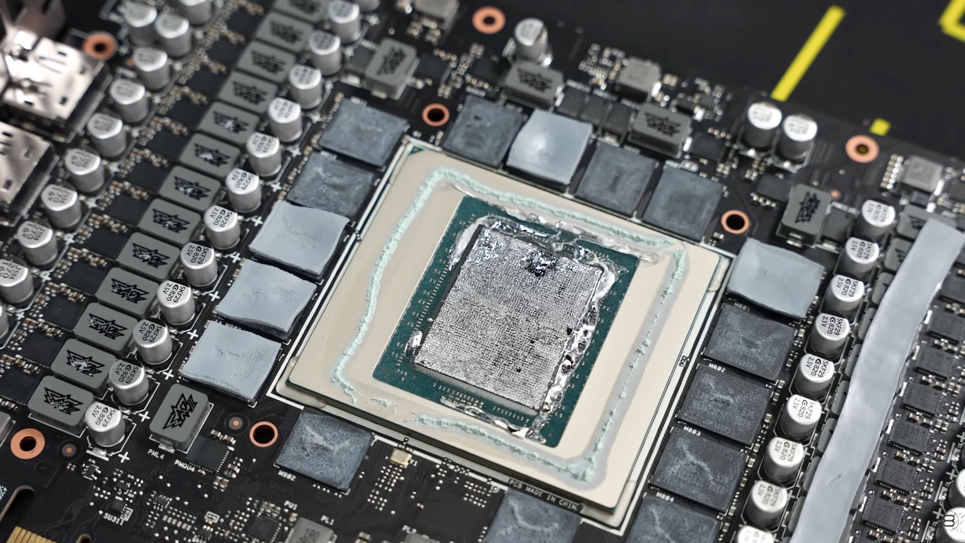 Μια κοντινή όψη μιας GPU σε ένα PCB κάρτας γραφικών με εφαρμοσμένη θερμική πάστα, που διαθέτει πολλαπλούς πυκνωτές και φάσεις ισχύος.