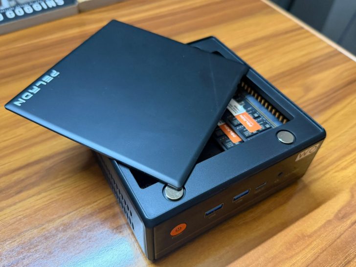 Ένας μίνι υπολογιστής Beelink με το καπάκι του μερικώς ανοιχτό, αποκαλύπτοντας δύο μονάδες RAM Kingston στο εσωτερικό, τοποθετείται σε ξύλινη επιφάνεια.