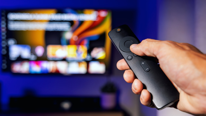 Ένα άτομο που χρησιμοποιεί ένα τηλεχειριστήριο για να ελέγξει μια έξυπνη τηλεόραση.