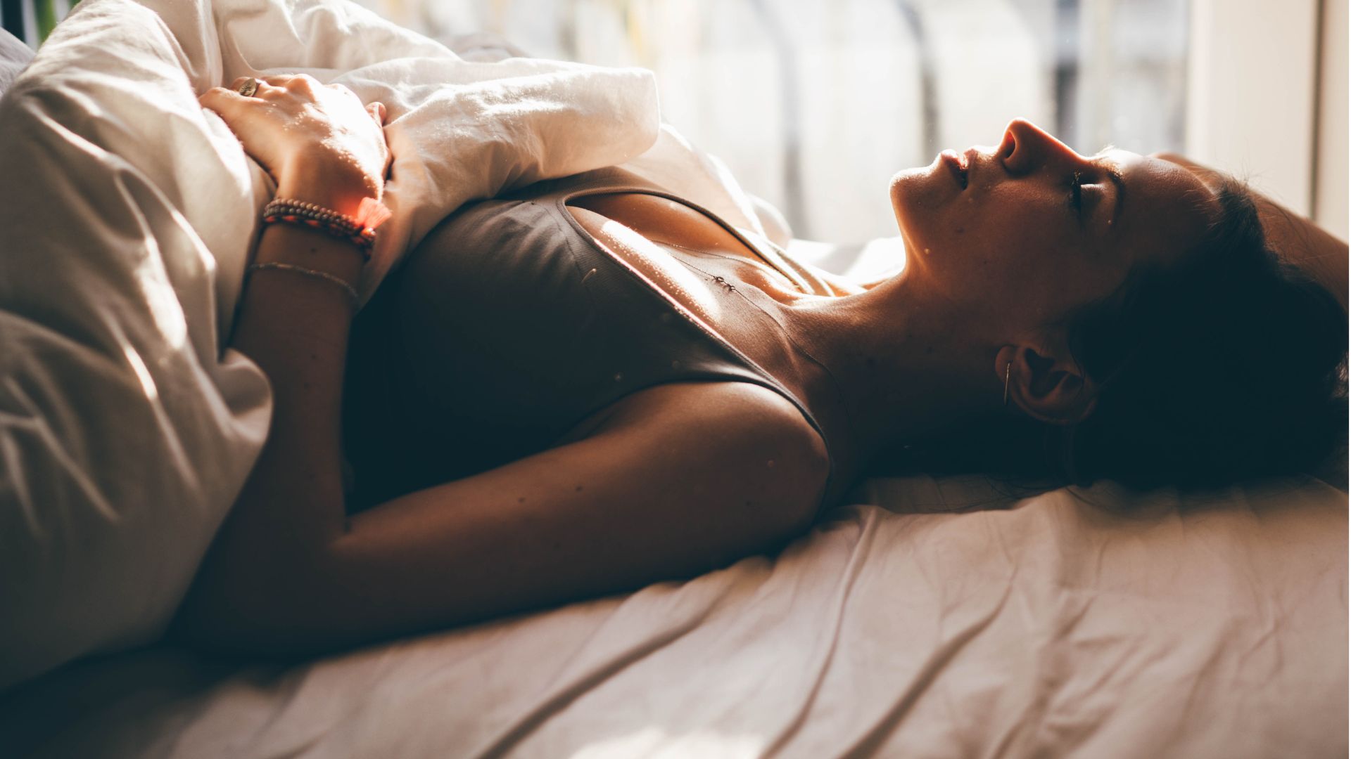 Μια γυναίκα ξαπλώνει ανάσκελα στο κρεβάτι με κλειστά μάτια.