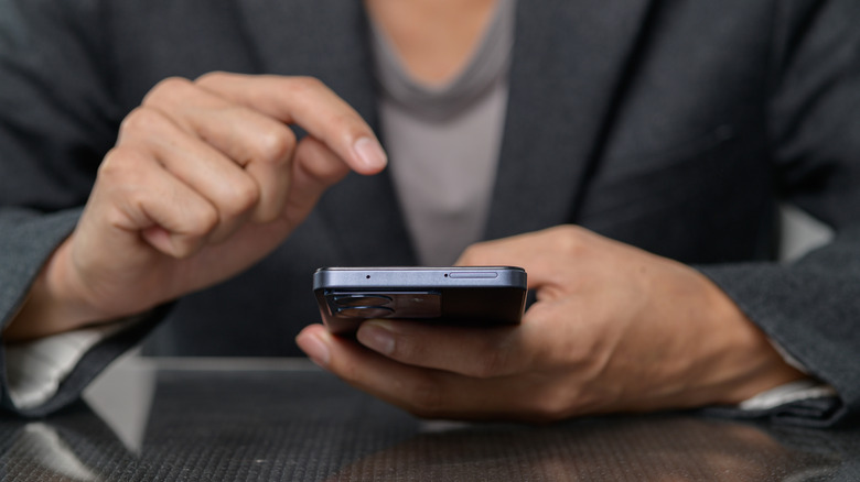 Ένα άτομο που κρατά το smartphone του με το δάχτυλό του να αιωρείται πάνω από την οθόνη