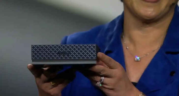 Ένα άτομο με μπλε σακάκι κρατά μια μικρή, μαύρη συσκευή AMD με ανάγλυφο σχέδιο.