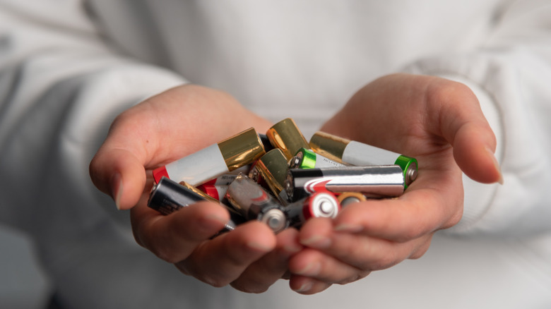 Δύο χέρια που κρατούν ένα μάτσο μπαταρίες.