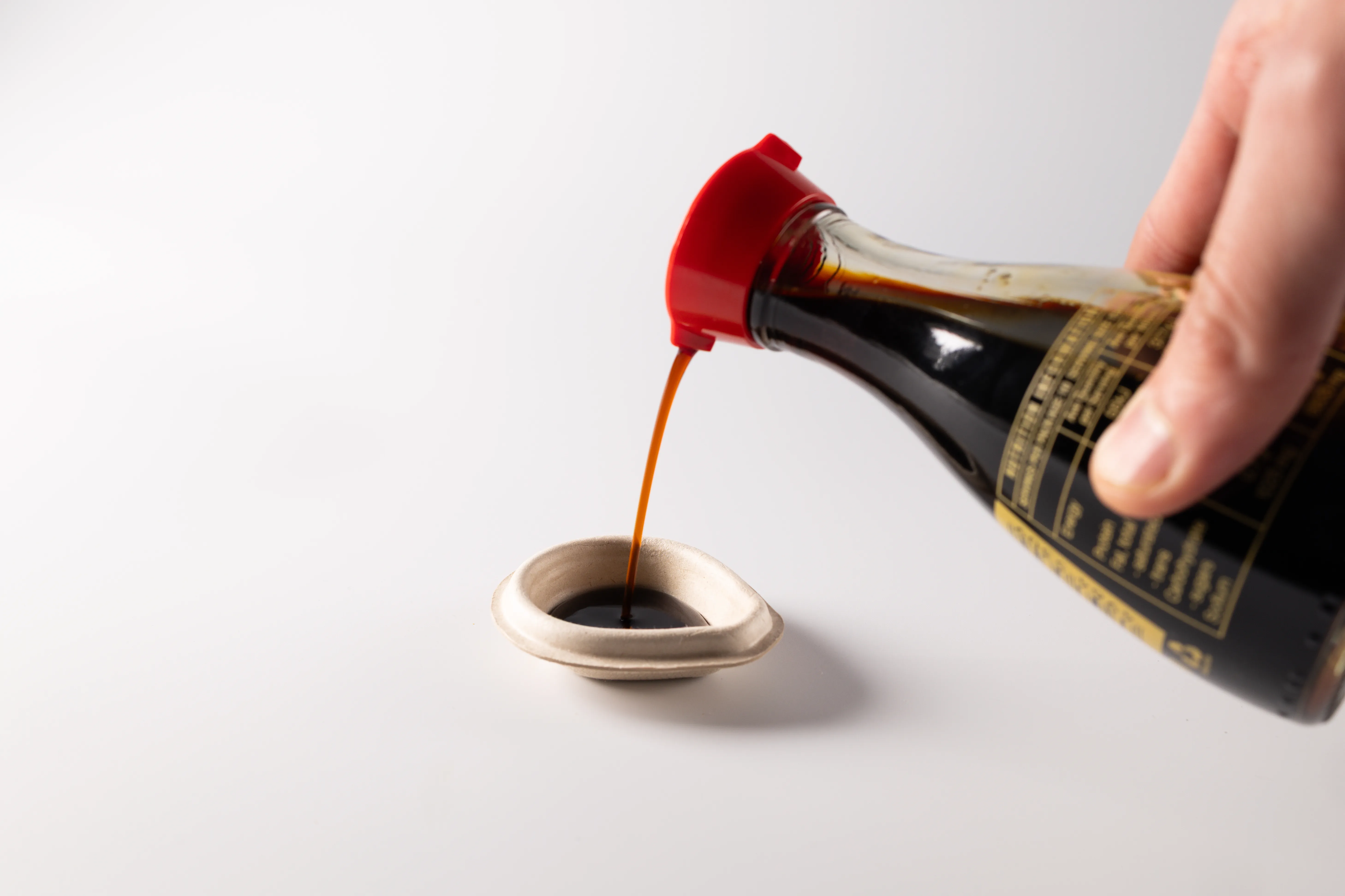 ένα χέρι που ρίχνει σάλτσα καφέ σόγιας σε ένα δοχείο