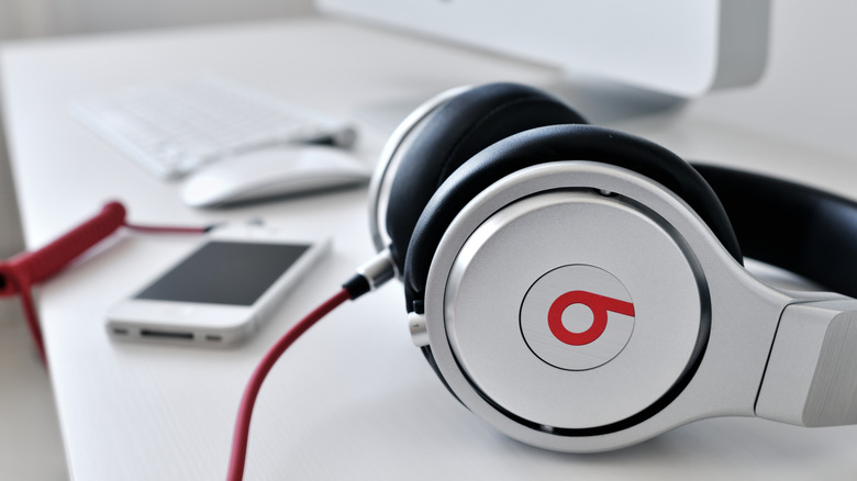 Ένα ζευγάρι αυθεντικά ακουστικά Beats σε ένα γραφείο με τηλέφωνο και υπολογιστή στο φόντο