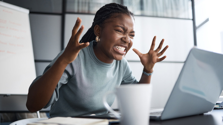 Ένας θυμωμένος χρήστης απεικονίζεται, κοιτάζοντας ένα φορητό υπολογιστή.